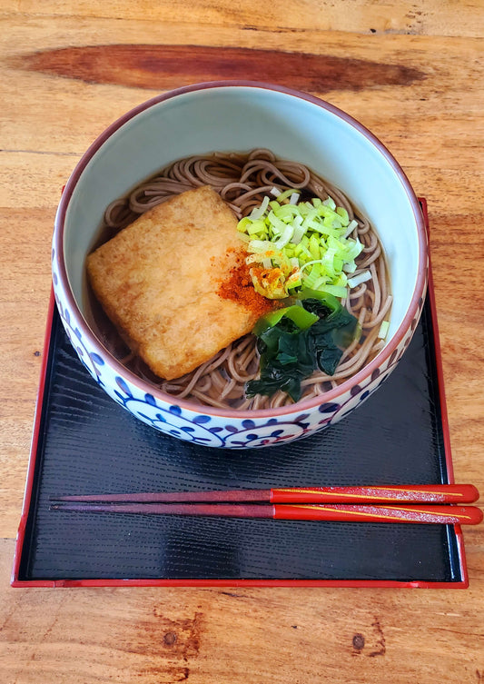 Kitsune soba japonais : bol de nouilles de sarrasin au bouillon dashi avec tofu frit, wakamé et poireau